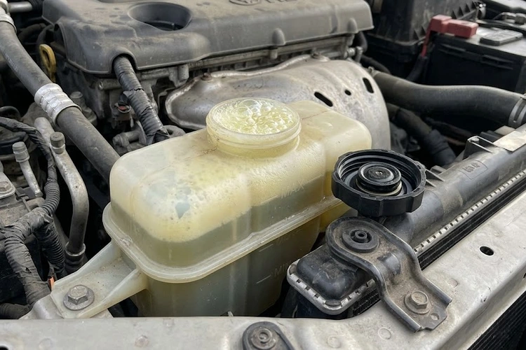 Coolant reservoir bubbling with visible foam and discoloration indicating a cooling system fault