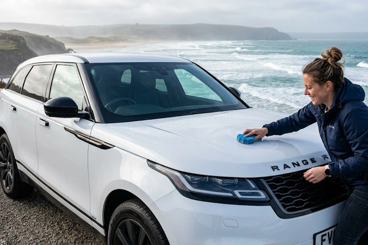 car paint protection coastal salt air — detailed sedan parked near ocean with protective coating applied