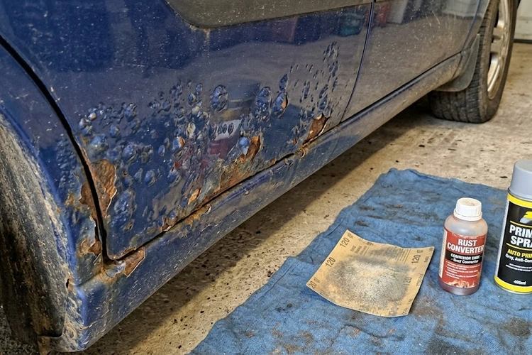 Paint bubbling on a car door panel showing raised blisters and rust damage beneath the clear coat