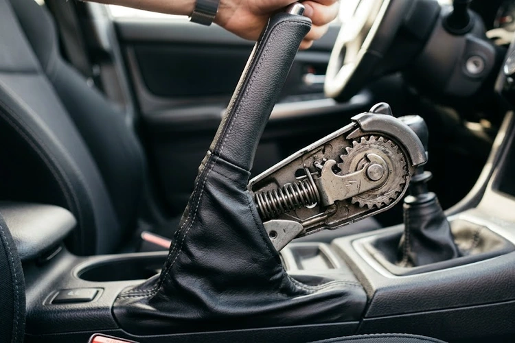 parking brake not holding — close-up of a seized rear drum brake and cable assembly on a vehicle