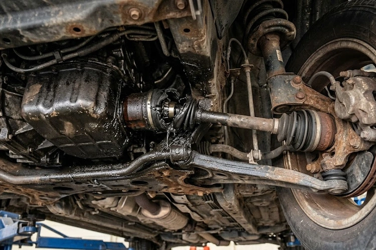 Mechanic inspecting CV joint axle boot for popping noise when turning
