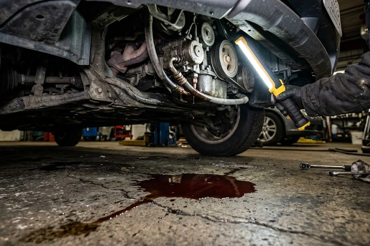 Power steering fluid leak pooling beneath the steering rack of a passenger vehicle