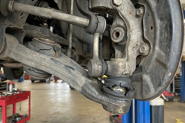 Mechanic inspecting suspension components underneath a vehicle to diagnose suspension creaking noise