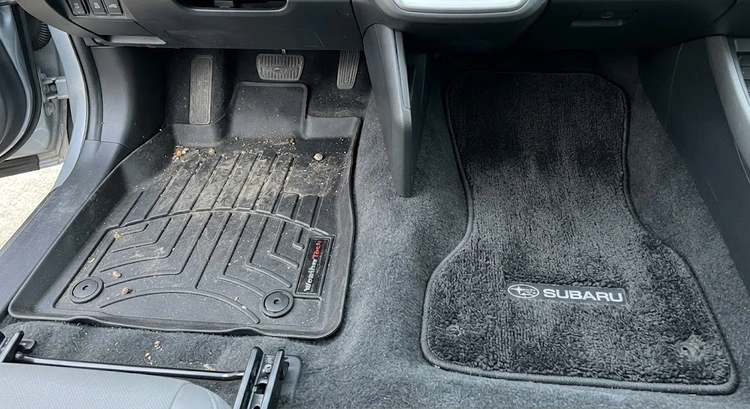 Side-by-side view of a heavy-duty rubber floor mat and a plush carpet floor mat inside a car footwell, showing texture and fit differences clearly.