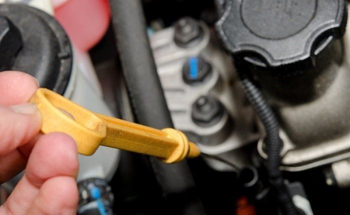 Pouring transmission fluid through a long funnel into the dipstick tube